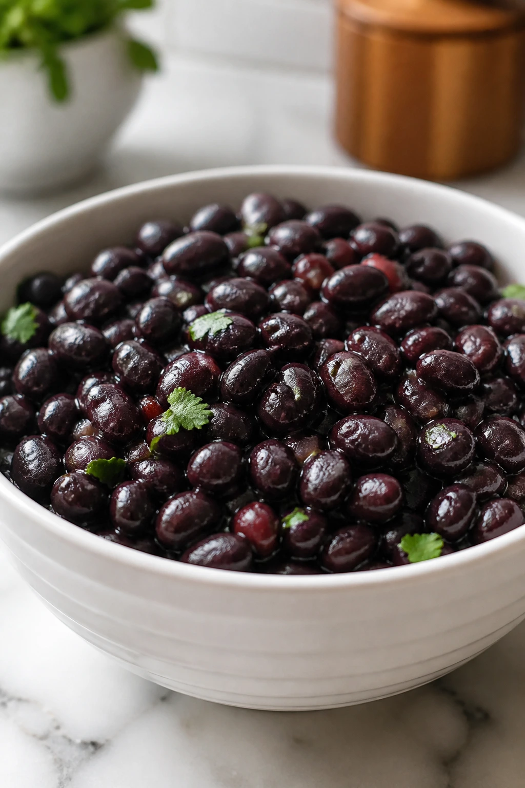 Glossy black beans in a white bowl on a simple kitchen counter