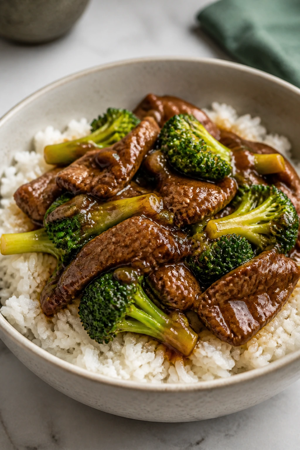 Beef and broccoli stir-fry over jasmine rice in a bowl.