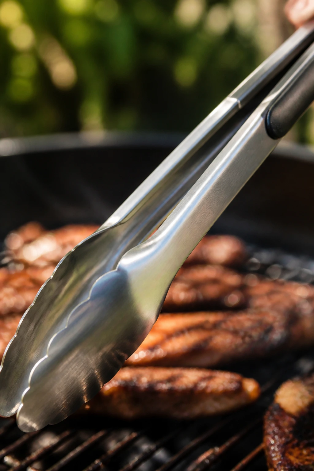 Close-up of stainless grilling tongs on a wooden surface