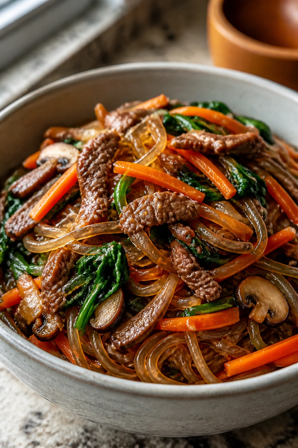 Japchae beef noodle bowl with colorful vegetables