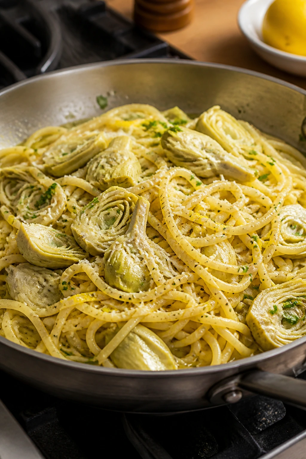 Close-up of glossy lemon artichoke pasta in a skillet
