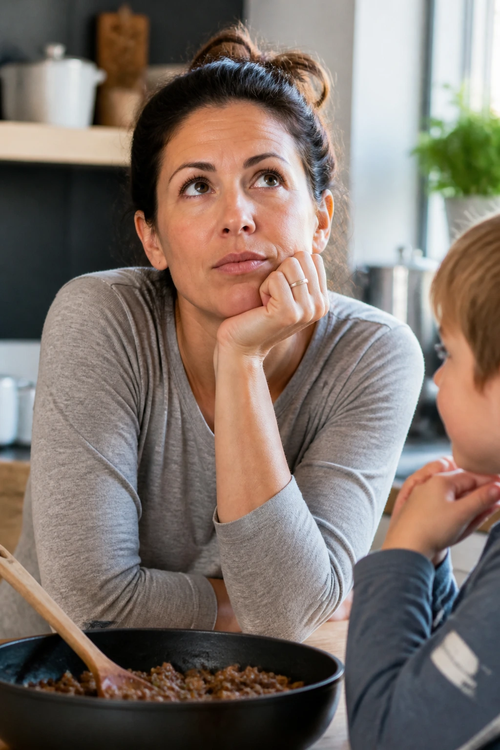 Real parent with child in a kitchen, thoughtful expression