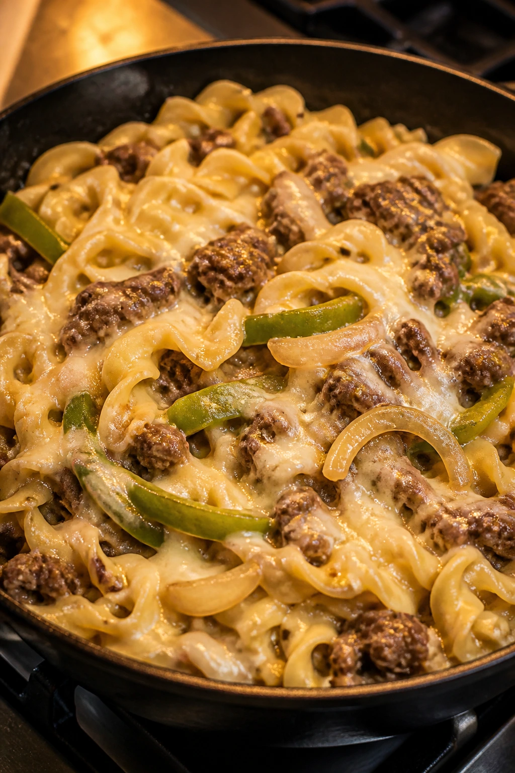 Philly cheesesteak pasta skillet in a hot pan with beef and cheese