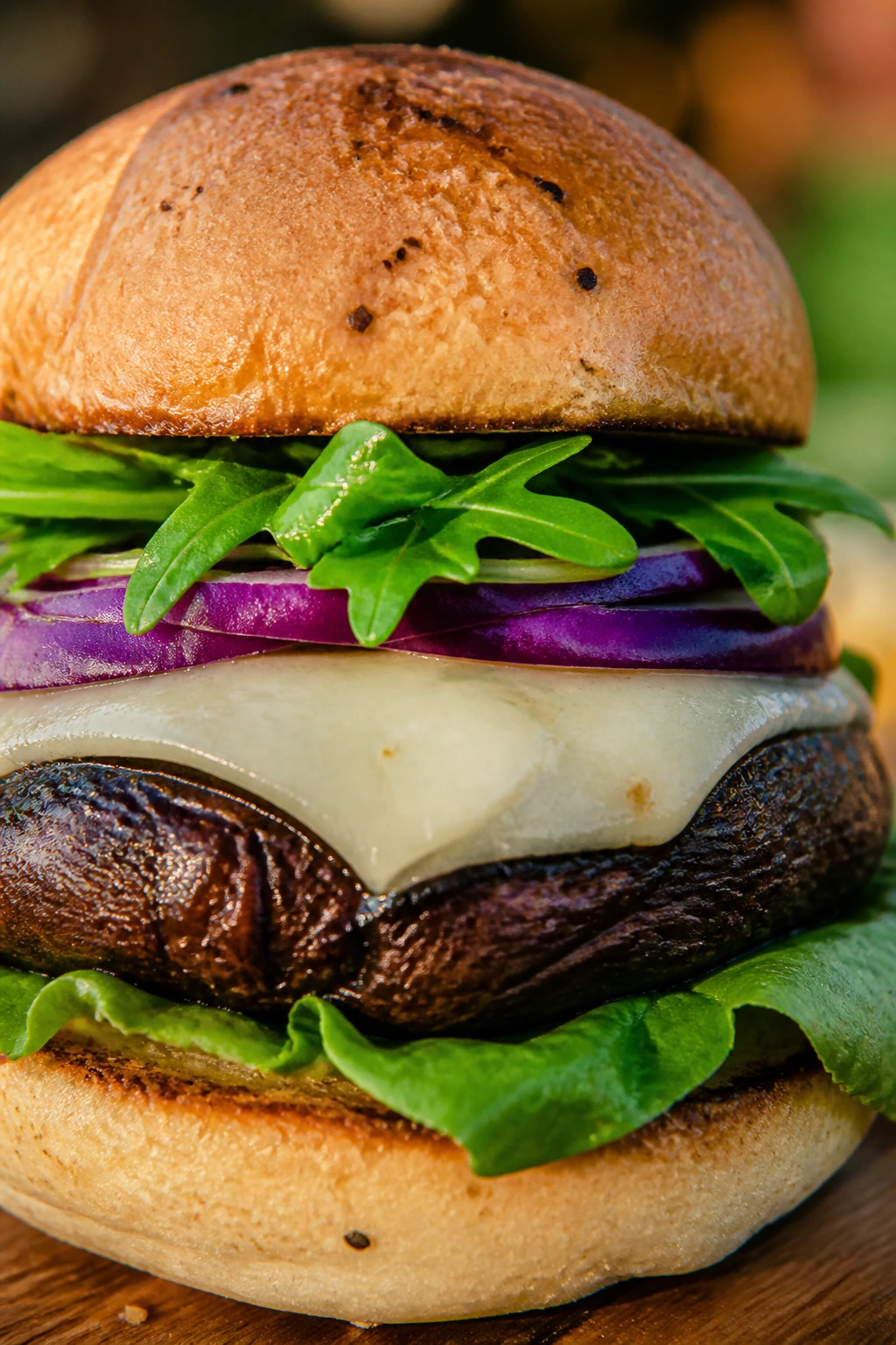 Grilled portobello mushroom burger on bun with greens
