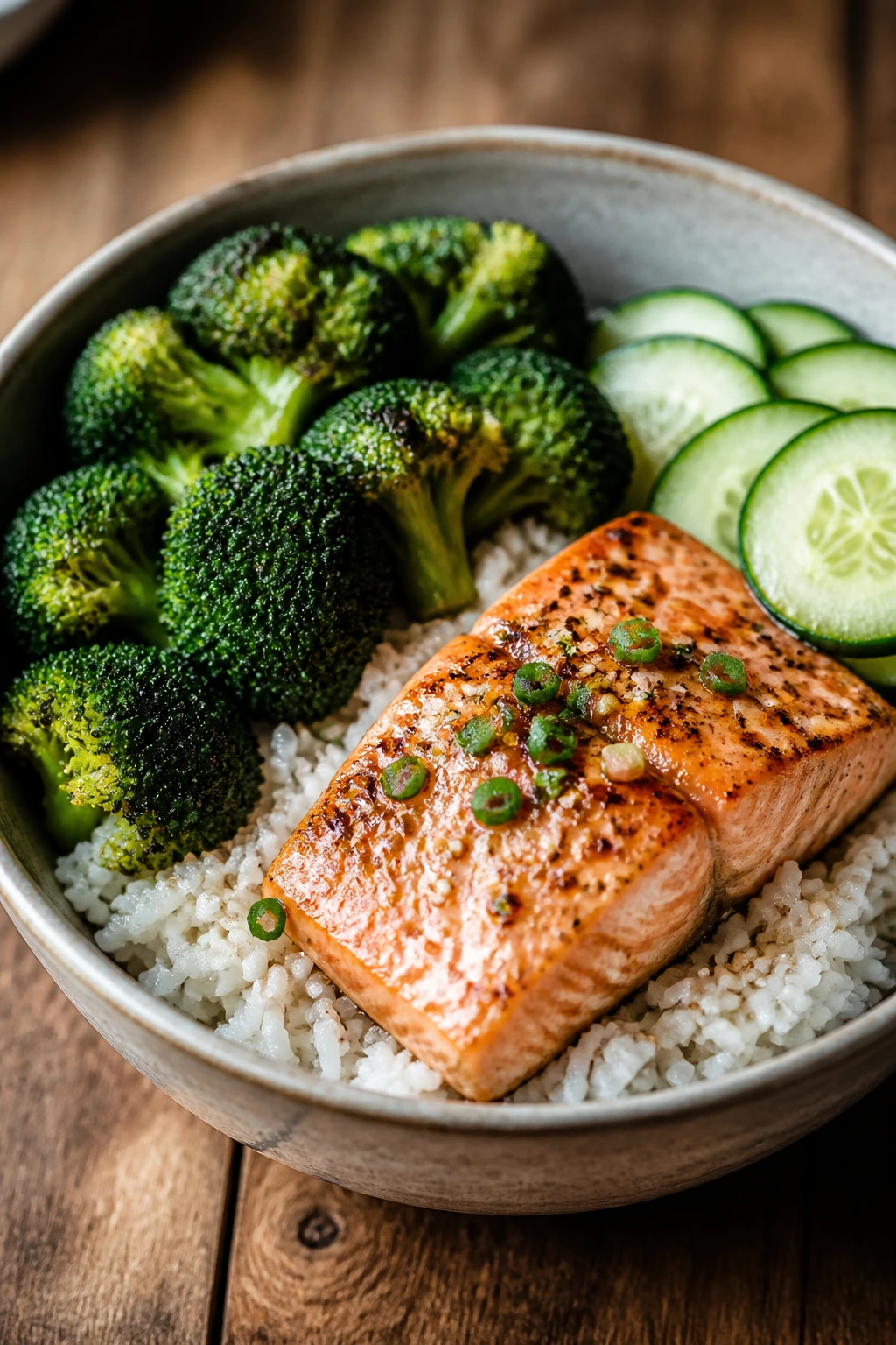 Close-up salmon bowl with rice, broccoli, and cucumber
