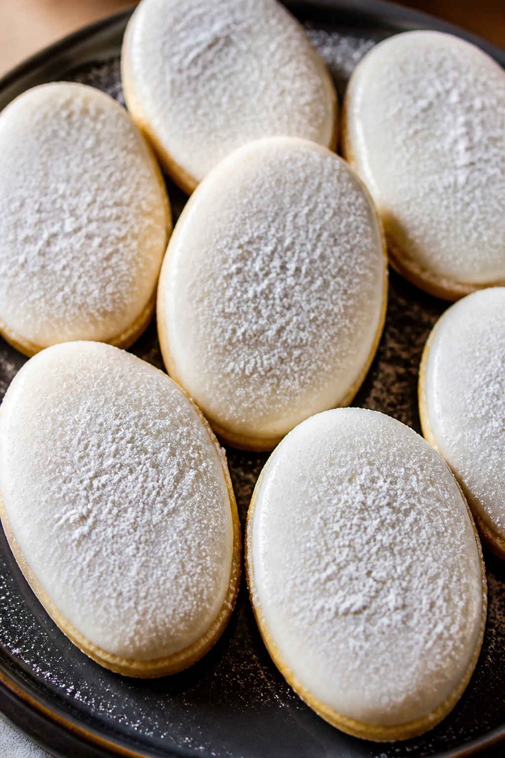Almond snow Easter egg cookies with powdered sugar on dark plate