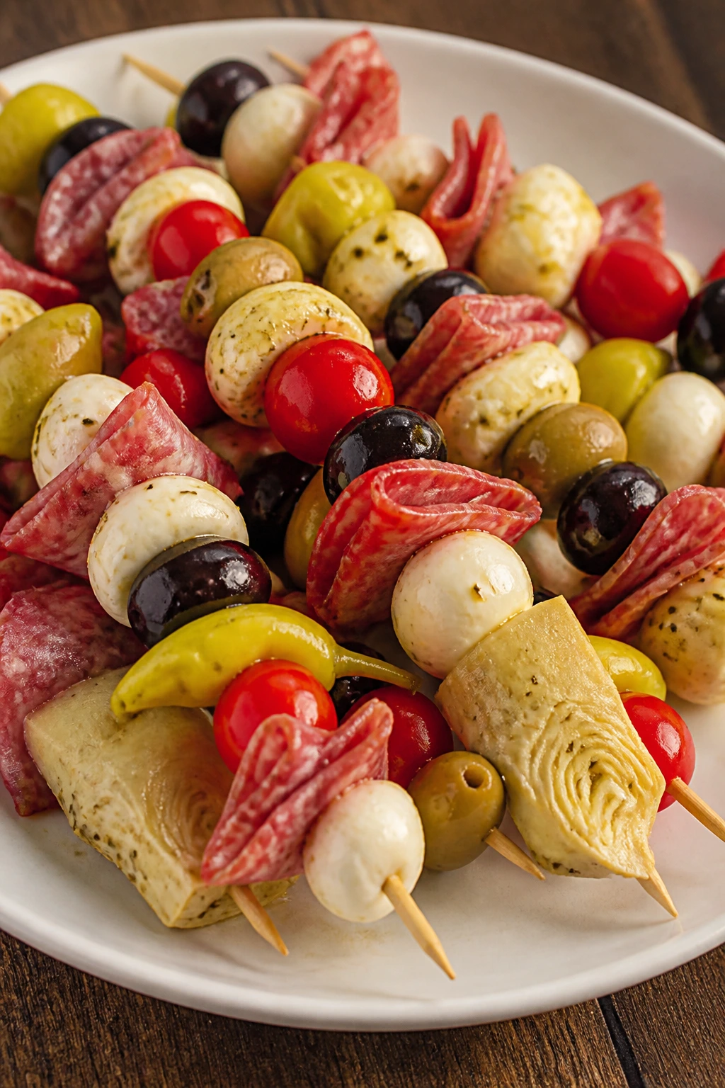 Antipasto skewers with salami mozzarella olives and vegetables on a platter