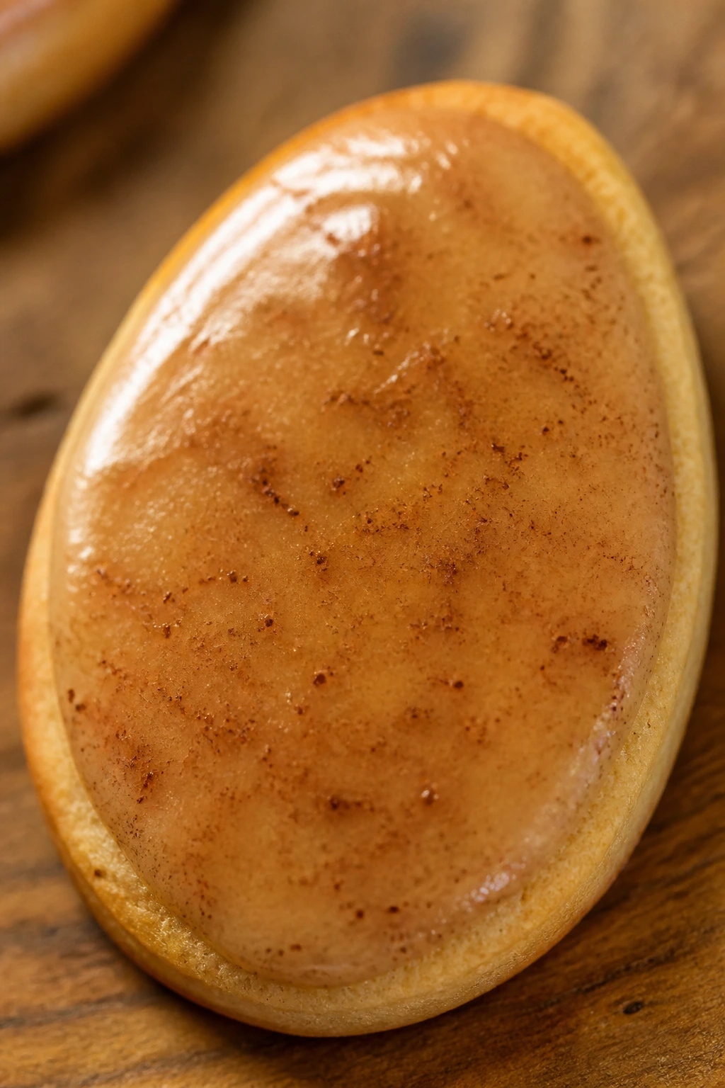 Close-up of an apple cinnamon Easter egg cookie dominating the frame with amber glaze