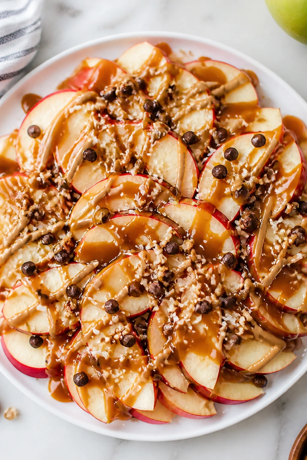 Apple nachos with caramel drizzle on a white plate