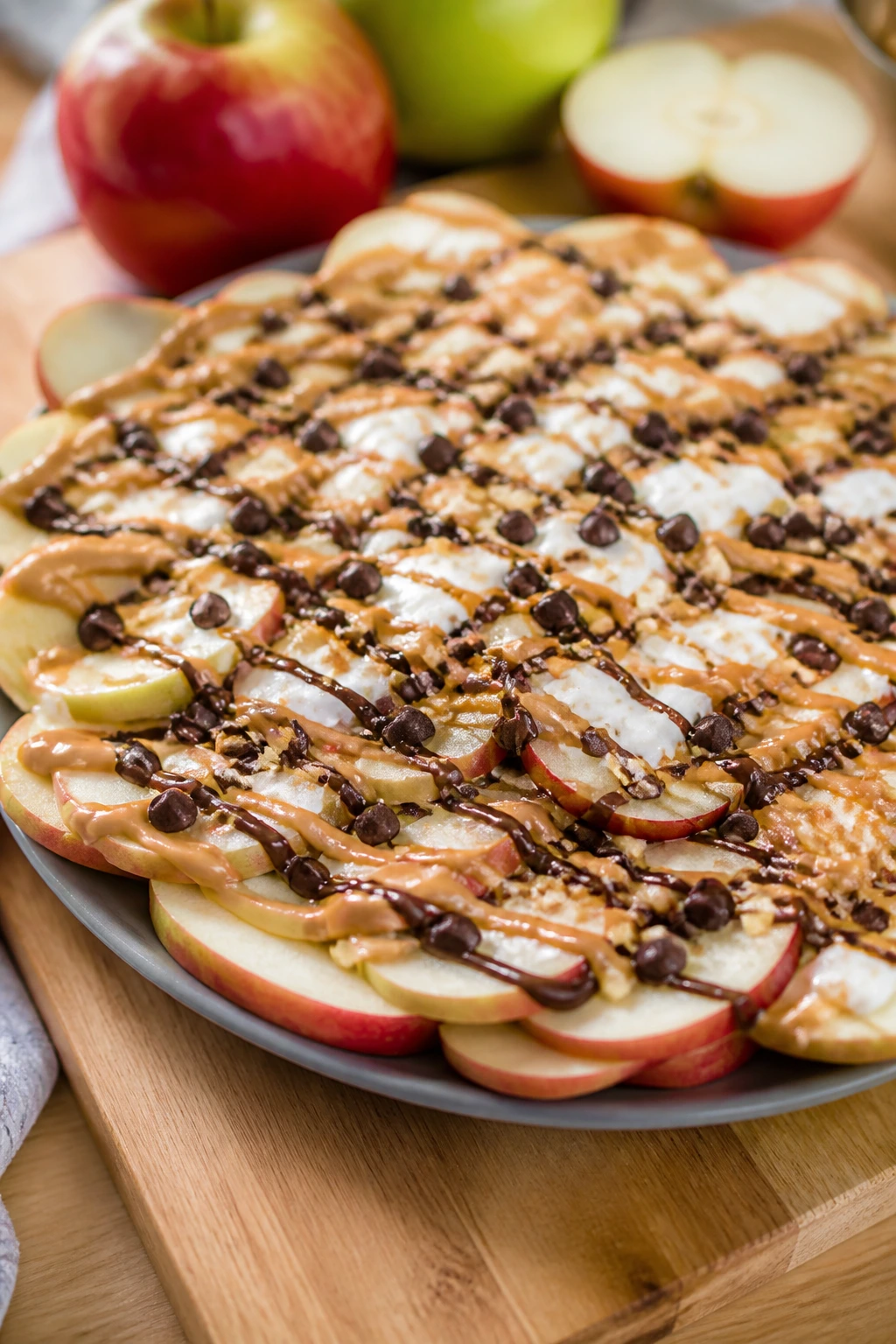 Apple nachos with peanut butter and yogurt toppings on a wooden platter