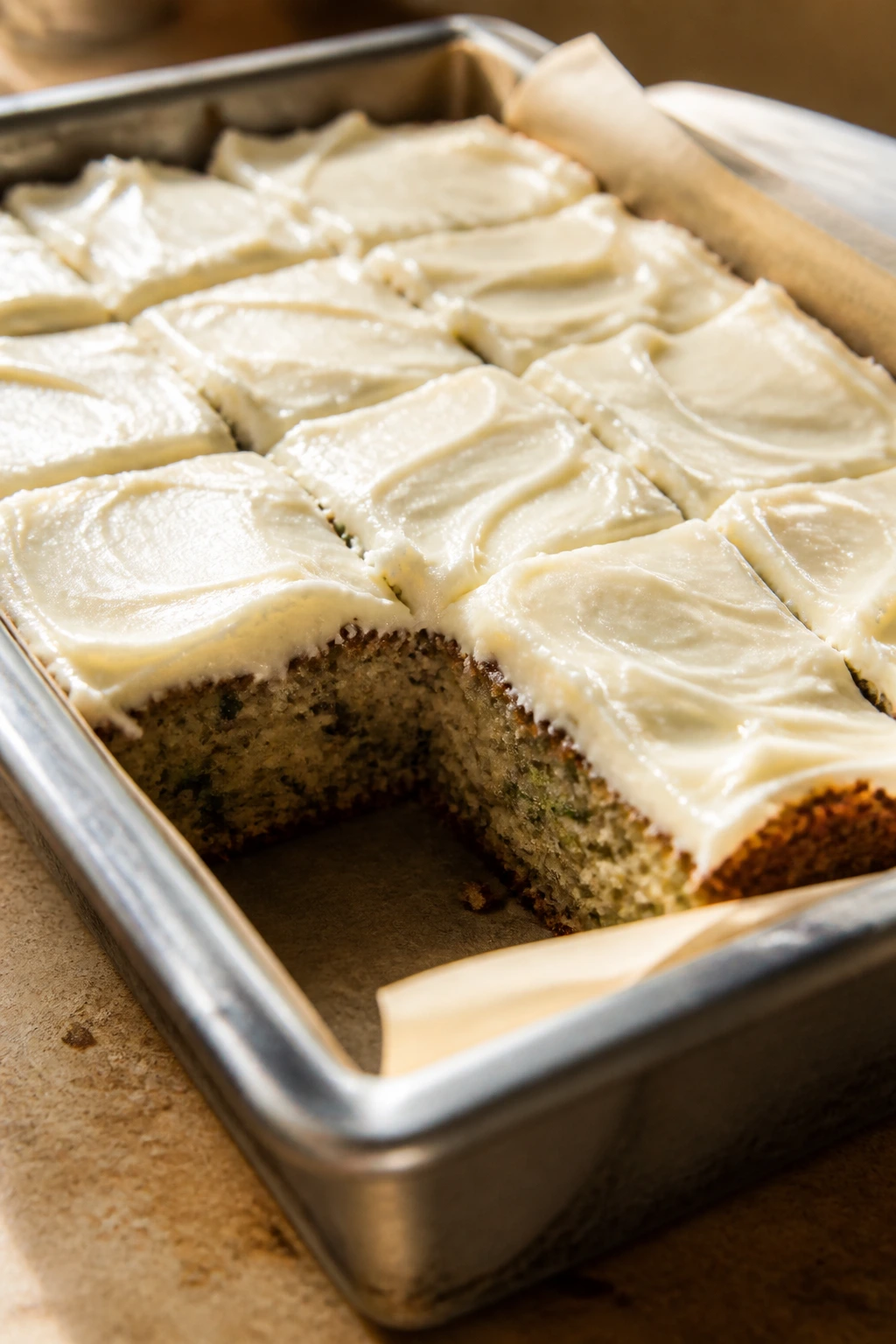 Metal baking pan with baked zucchini bars on a kitchen counter