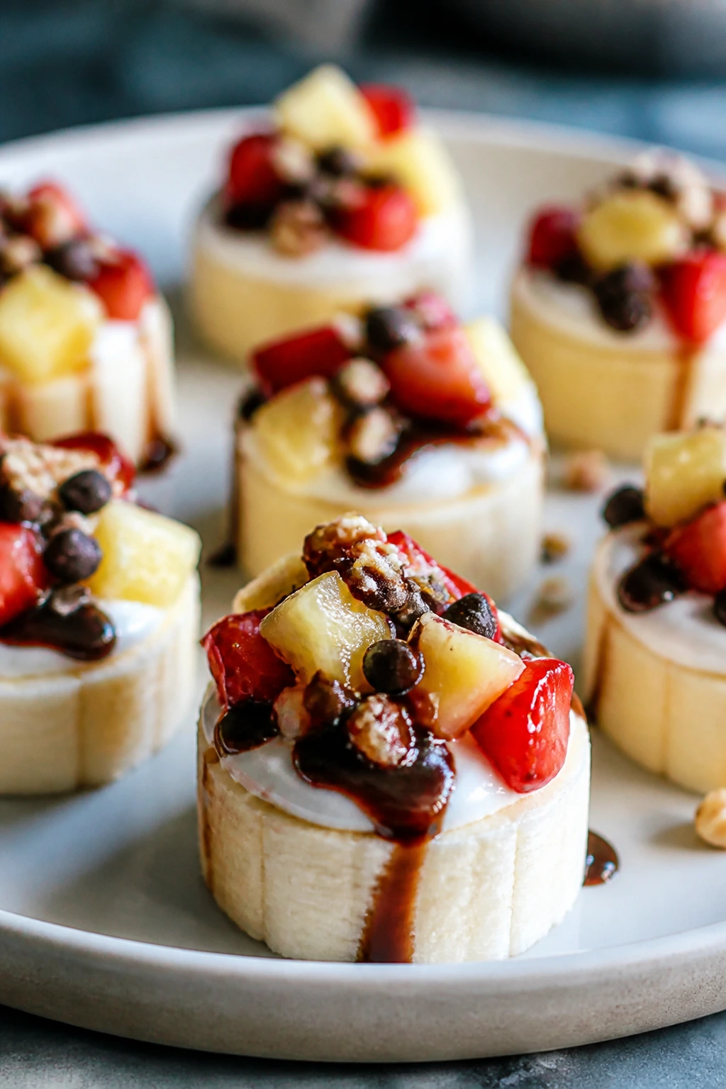 Banana bites topped with yogurt and fruit on a chilled plate