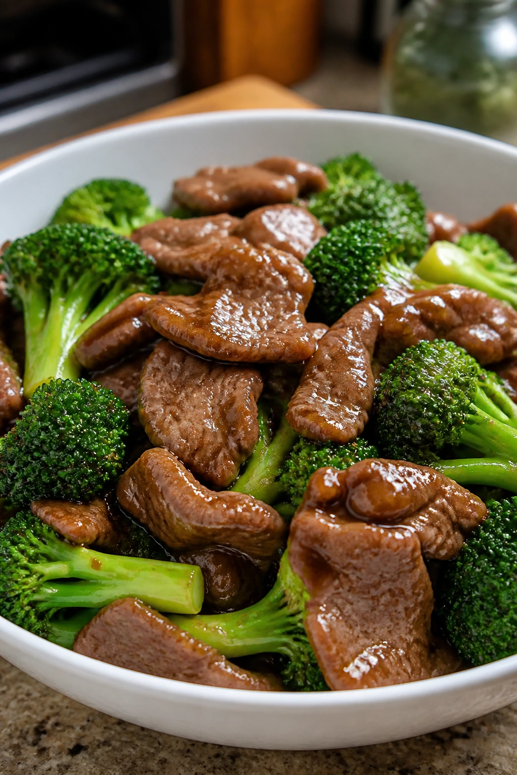 Glossy beef and broccoli stir-fry in white bowl with sauce clinging