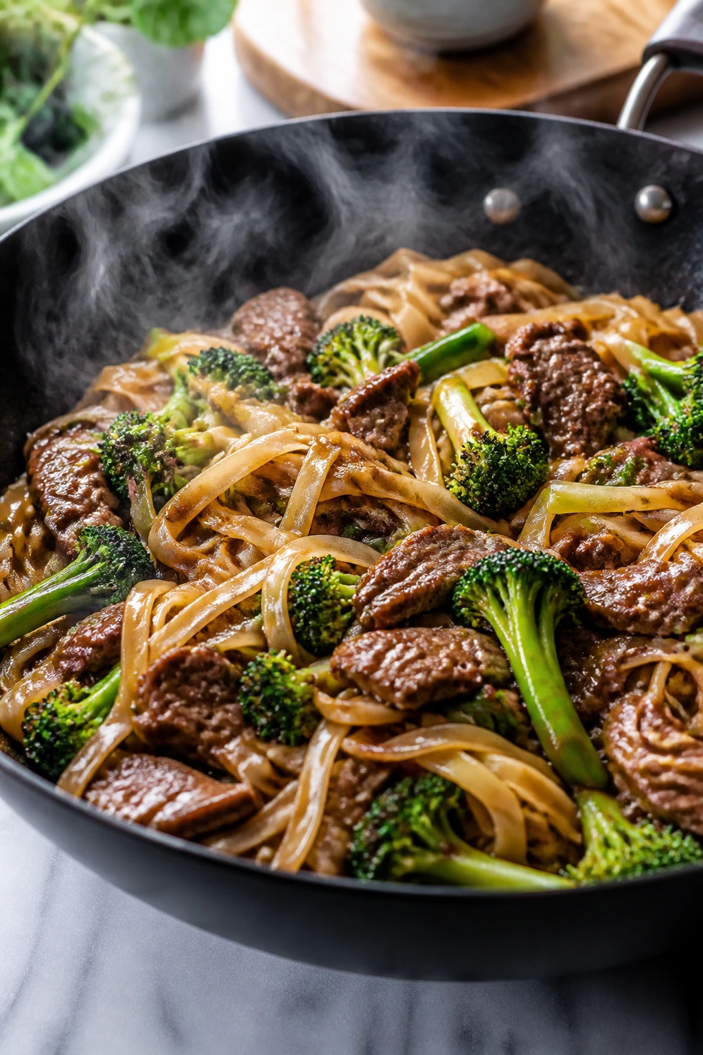 Glossy beef and broccoli rice noodle stir-fry in a wok