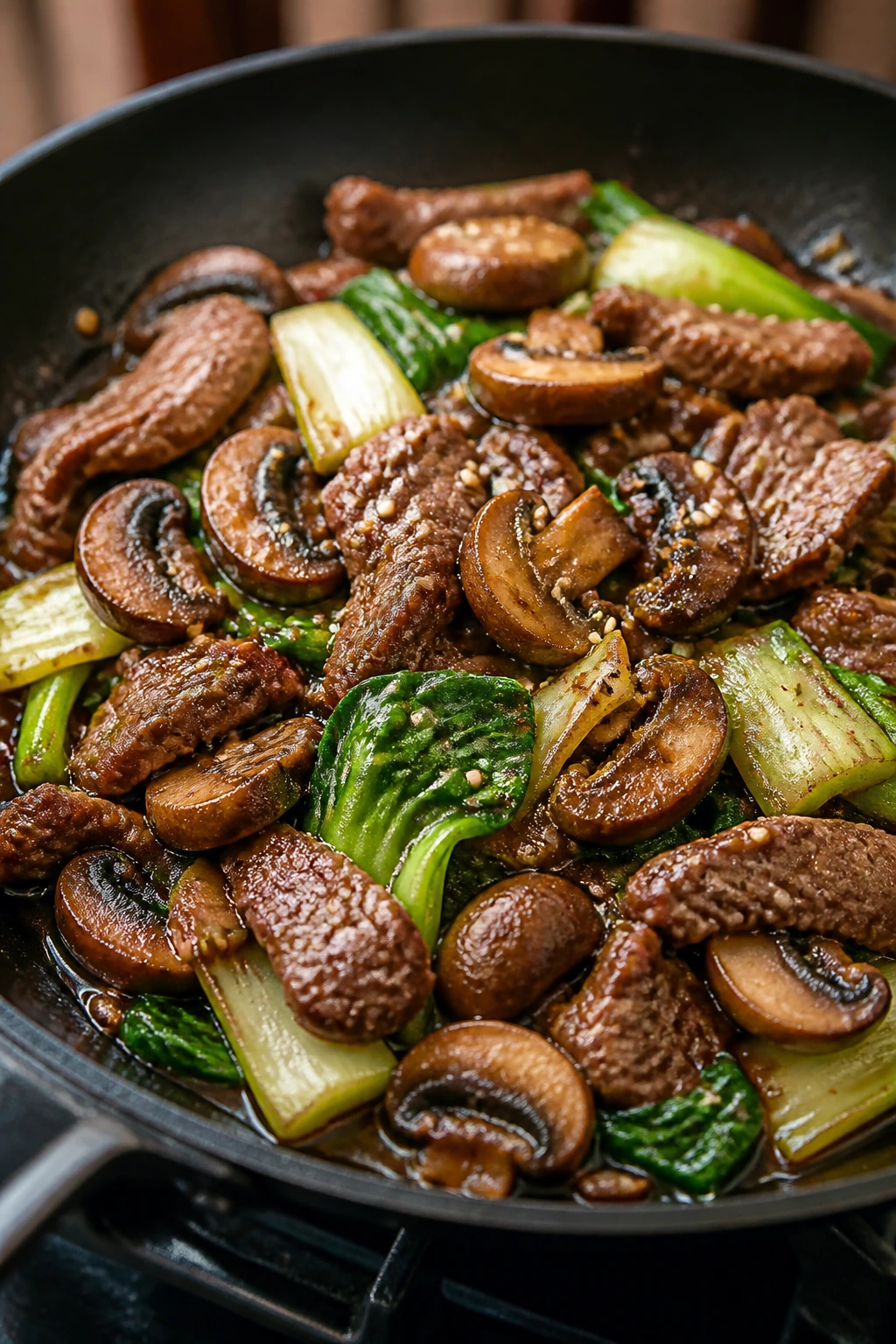Beef and mushroom stir-fry with sesame in a wok.