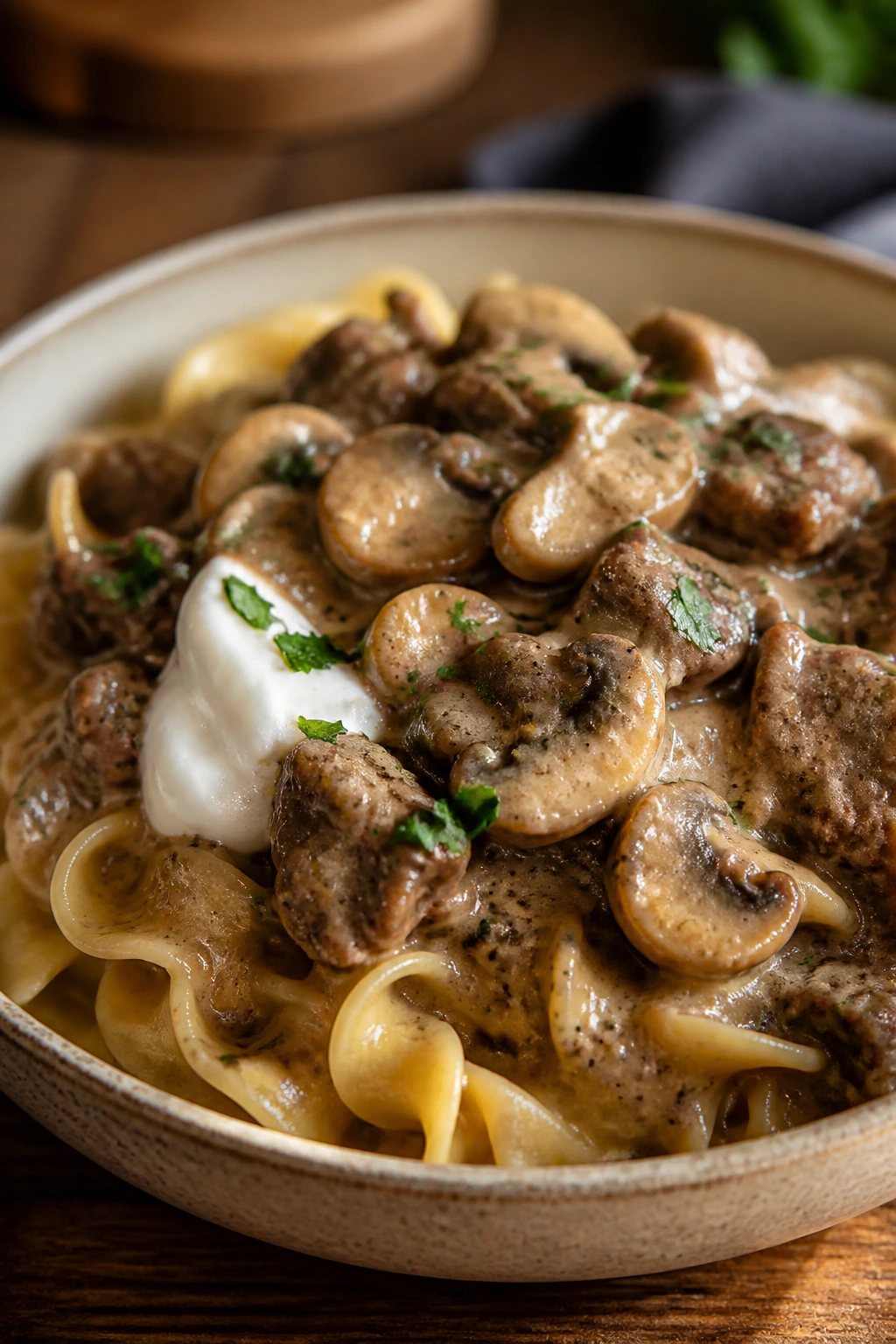Creamy beef stroganoff with mushrooms in a bowl on a wooden table.