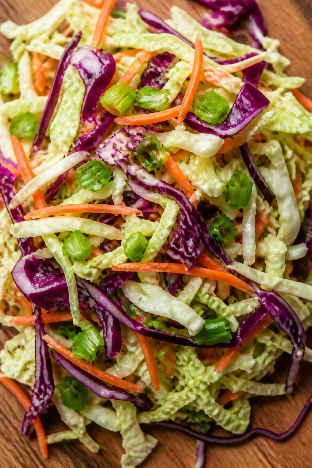 Colorful cabbage with carrots and scallions on cutting board