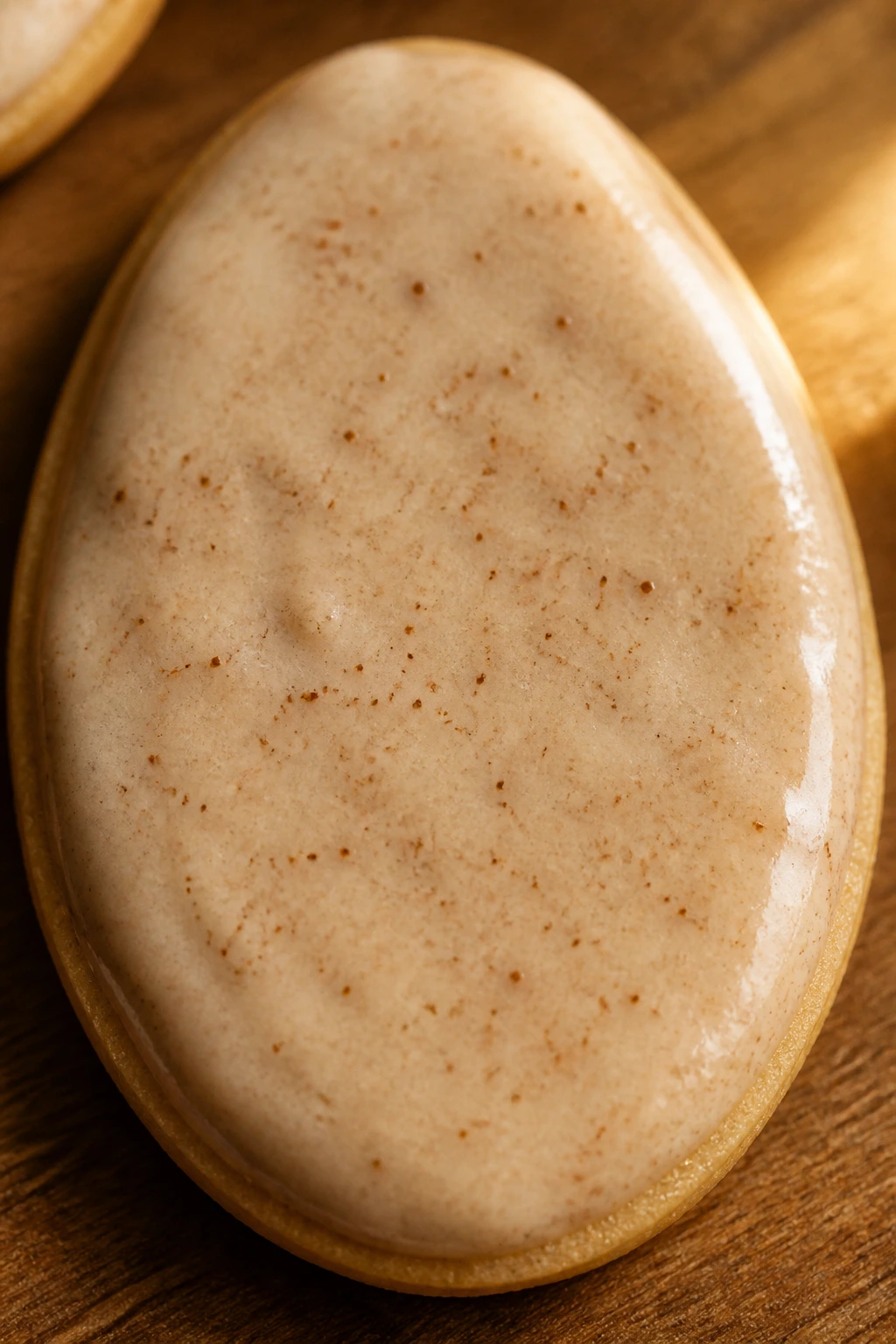 Close-up of chai-spice Easter egg cookie with cinnamon specks on a wooden kitchen counter