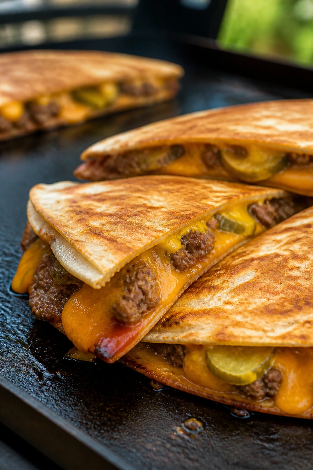 Close-up of cheeseburger quesadilla wedges on a hot griddle.