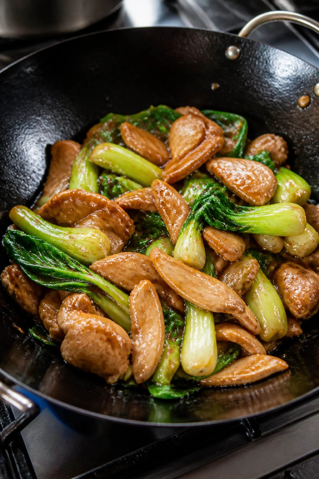 Medium close-up of chicken and bok choy with oyster sauce in a wok
