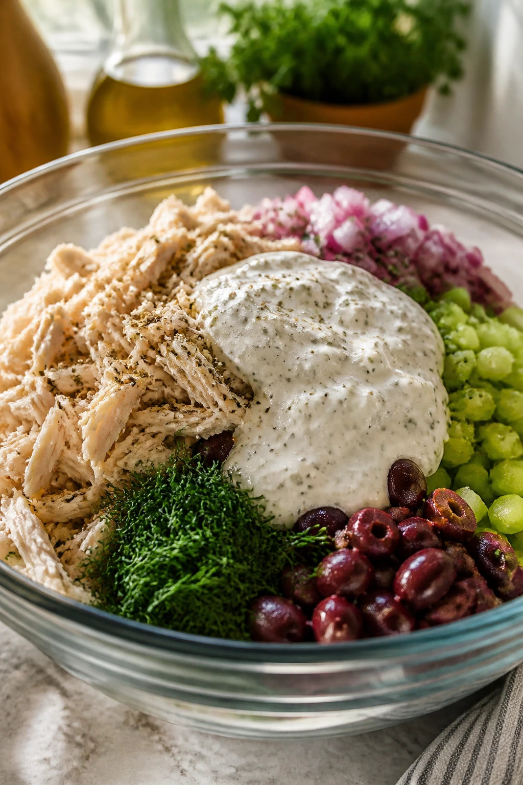 Close-up of chicken chunks and glossy yogurt dressing in a bowl, showing texture contrasts.