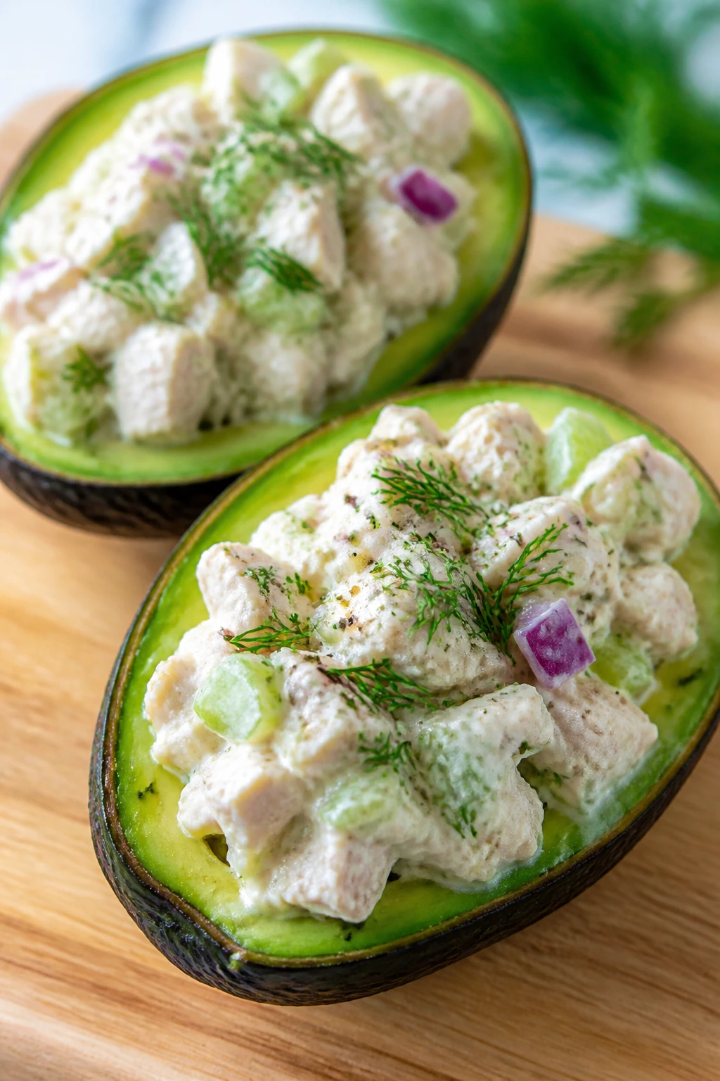 Two avocado halves filled with Greek yogurt chicken salad