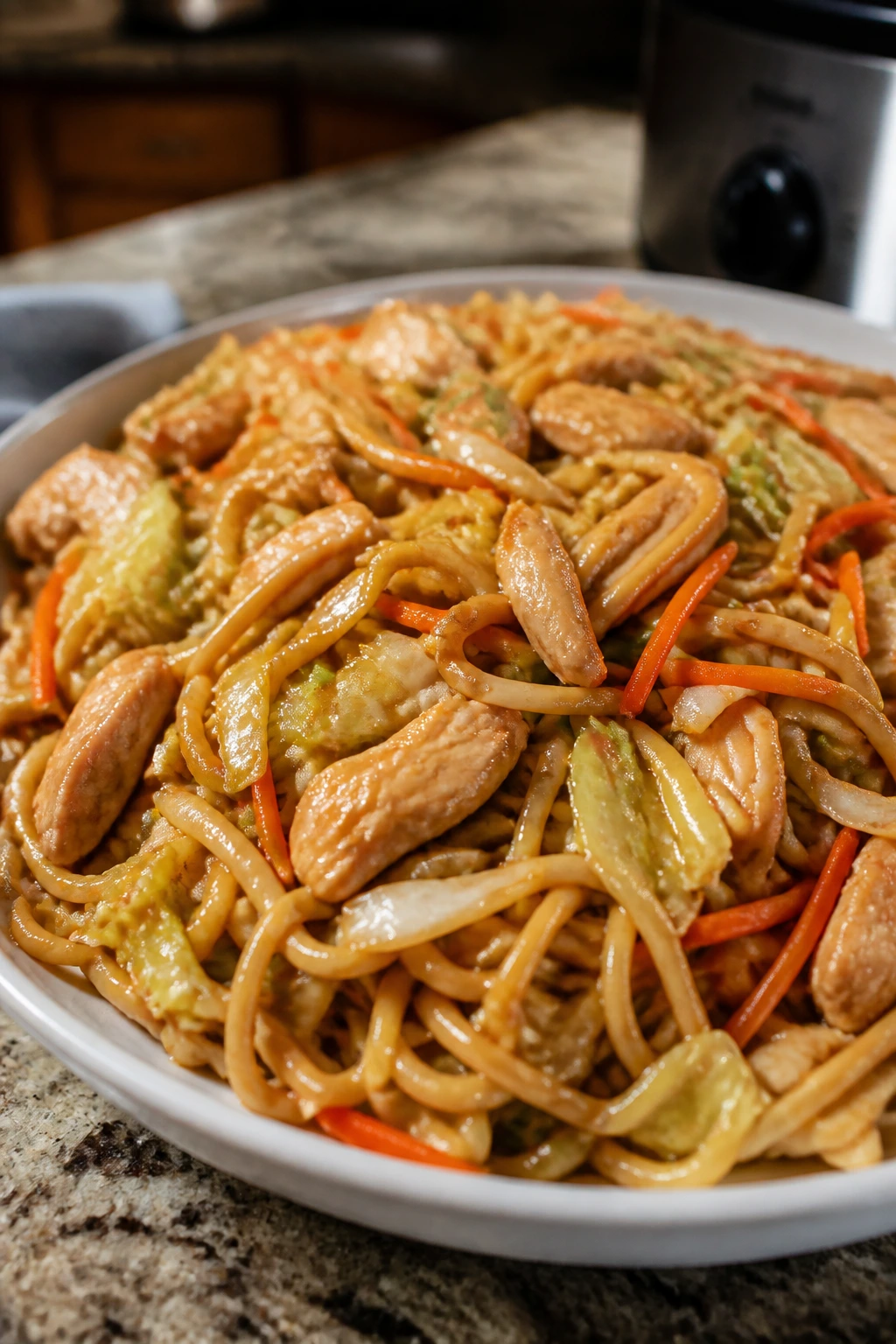 Plate of chicken chow mein with cabbage and carrots