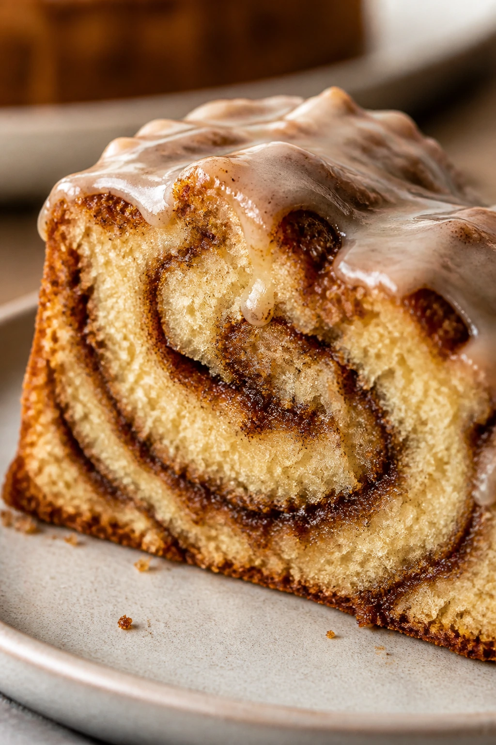 Close-up of cinnamon roll cake slice with glaze on plate