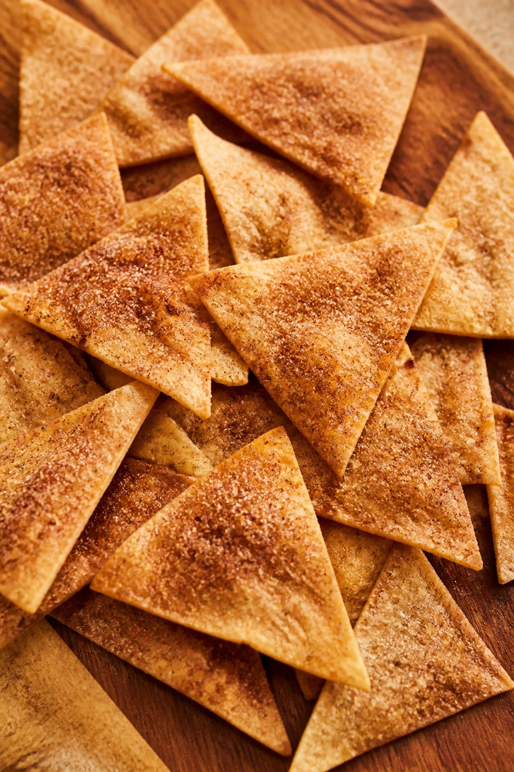 Pile of cinnamon sugar tortilla chips on a wooden board