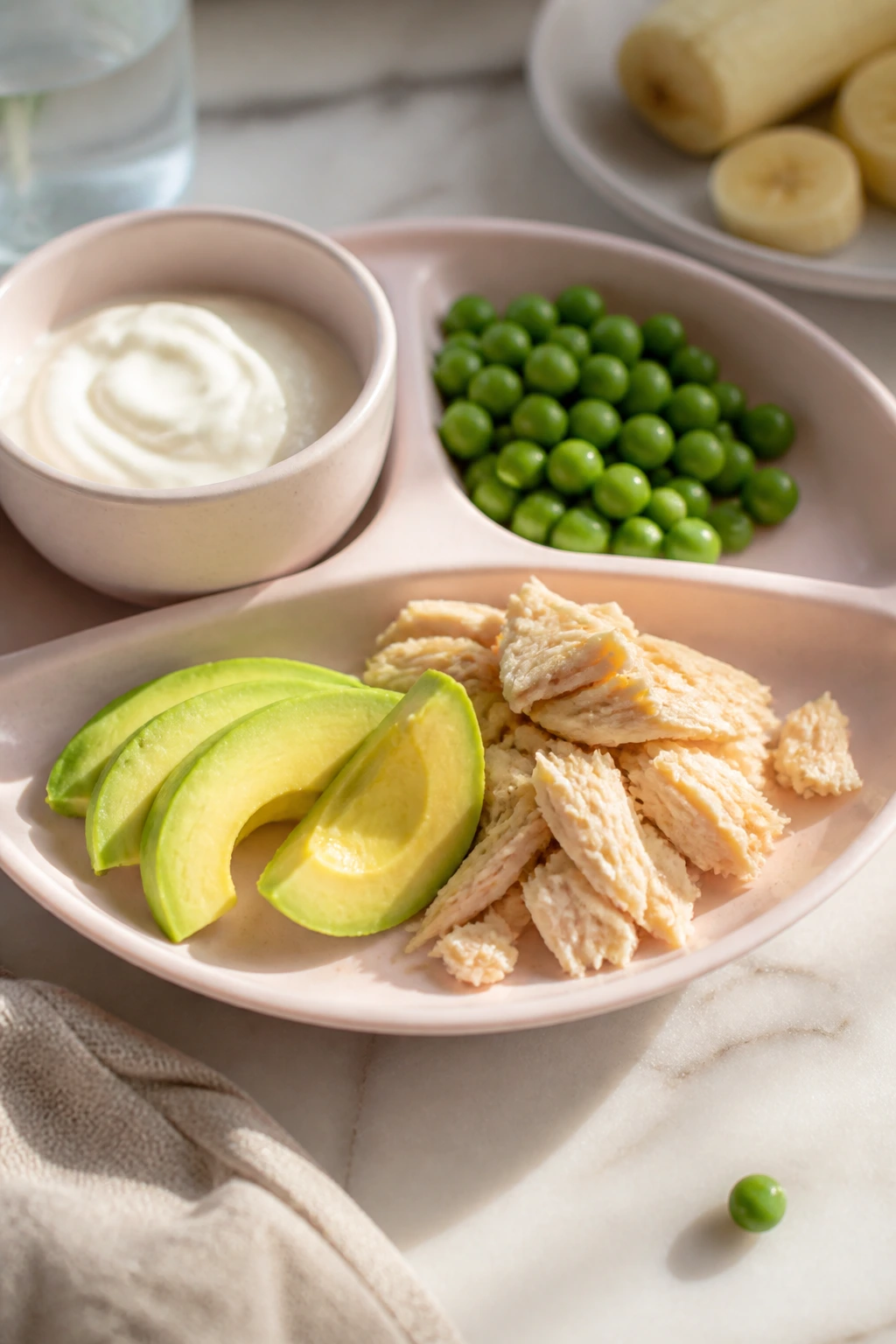 Plate with yogurt, peas, and avocado on a bright table.