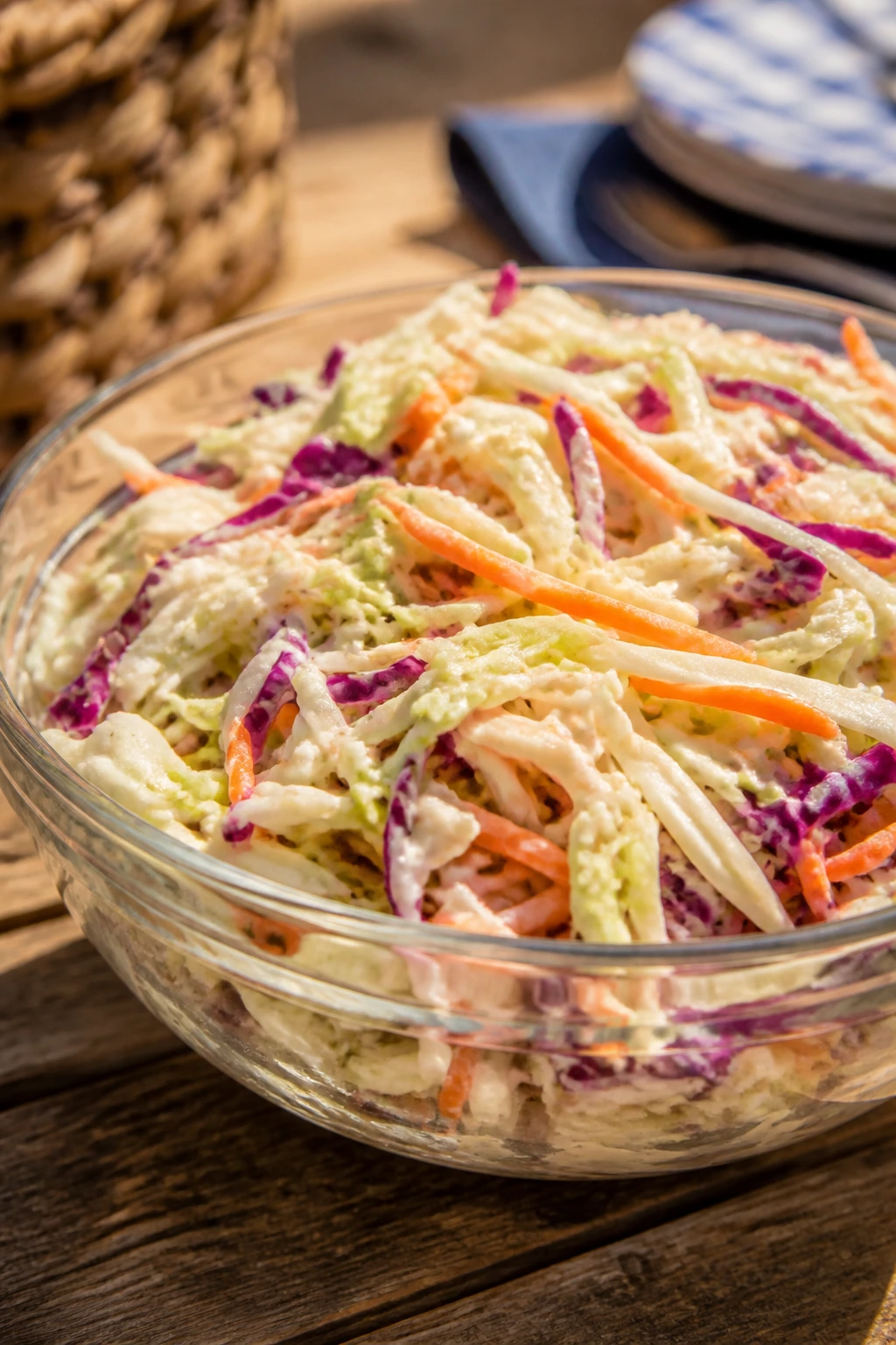 Crisp coleslaw in a glass bowl on a sunny picnic table