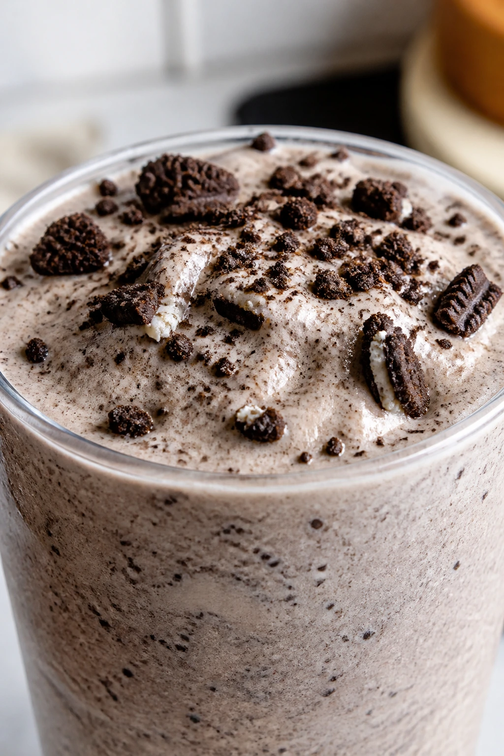 Cookies and cream smoothie with cookie bits in a glass on a kitchen counter