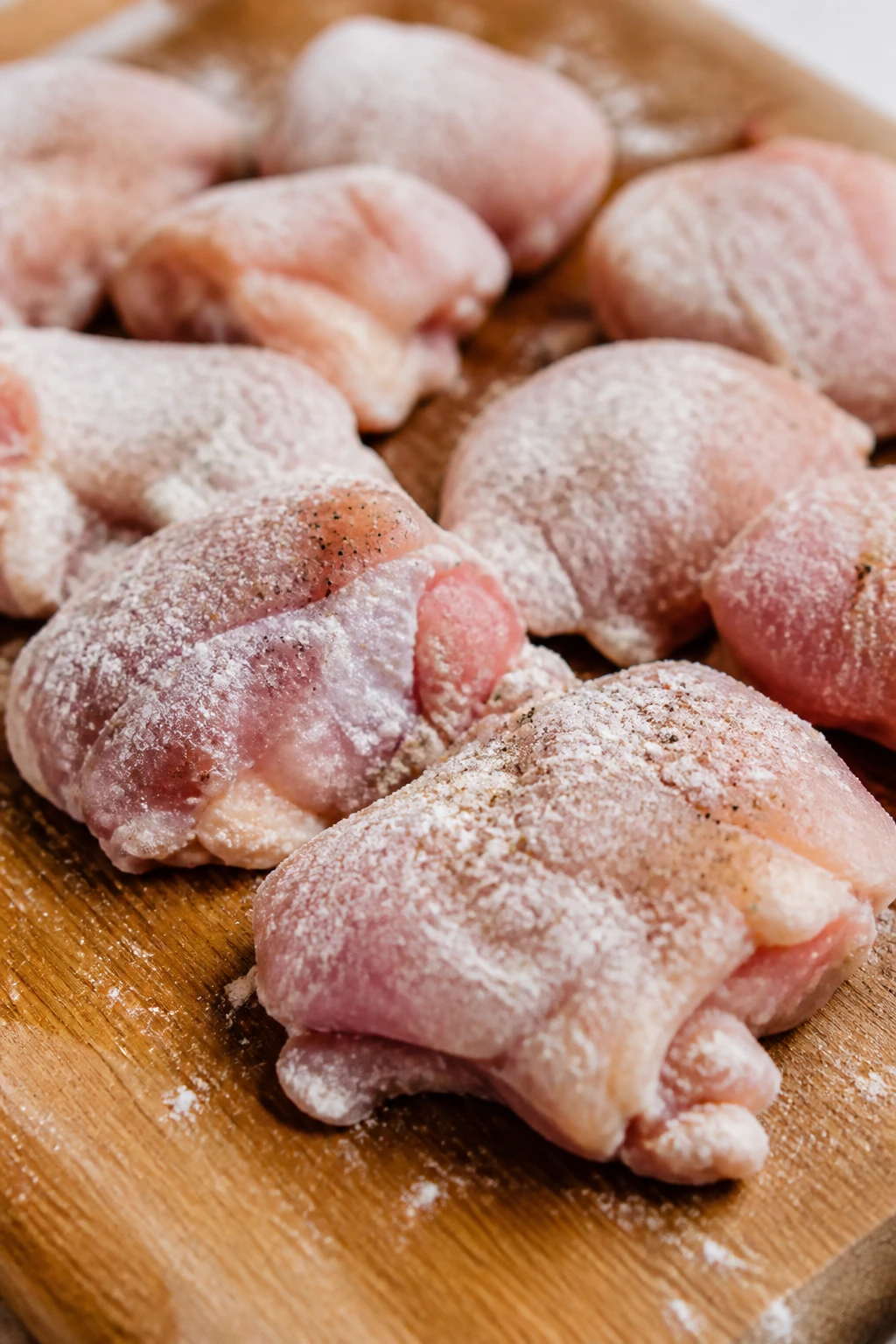 Cornstarch-dusted chicken thighs on a cutting board