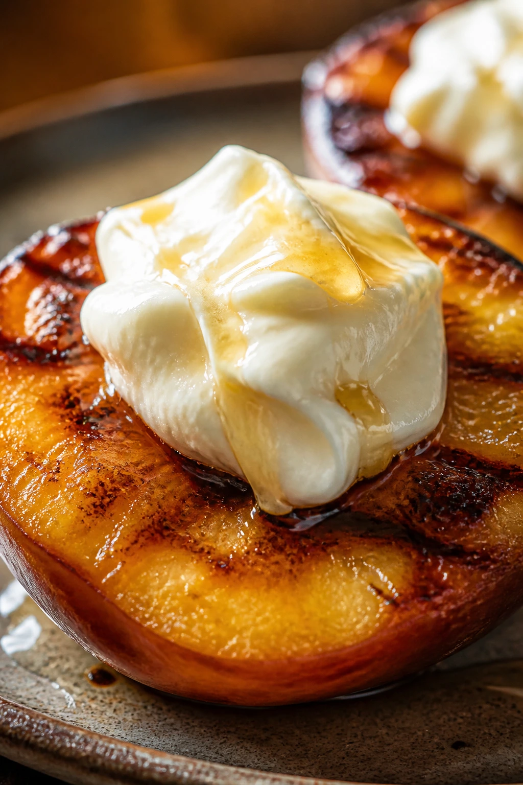 Soft mound of cream cheese frosting on warm grilled fruit with honey drizzle
