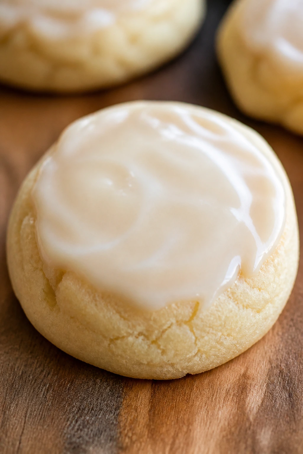 Close-up of a cream cheese sugar cookie with a light glaze on a wooden board