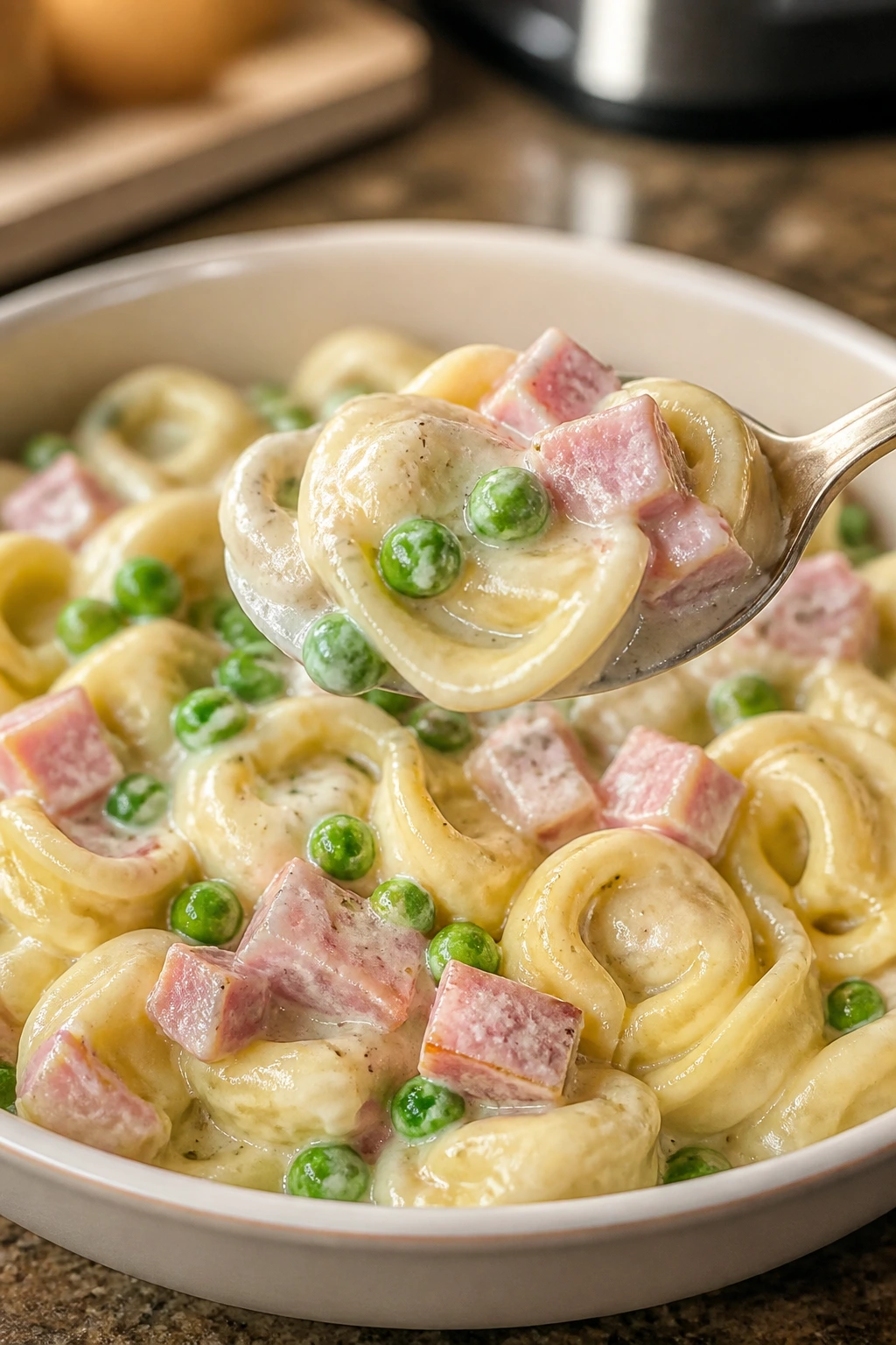 Creamy ham and pea tortellini on a plate with ham and peas