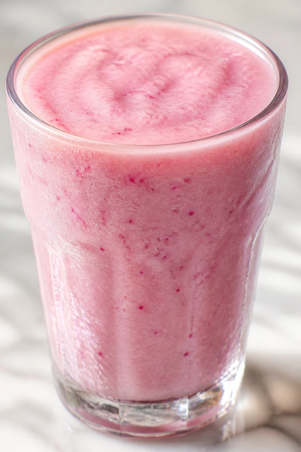 Close-up of pale pink Dragon Fruit Lychee Smoothie in a glass on a marble counter