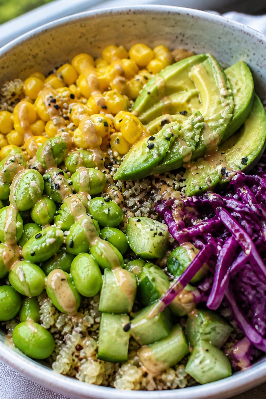 Close-up of a vibrant edamame corn quinoa bowl with avocado and cabbage in a kitchen