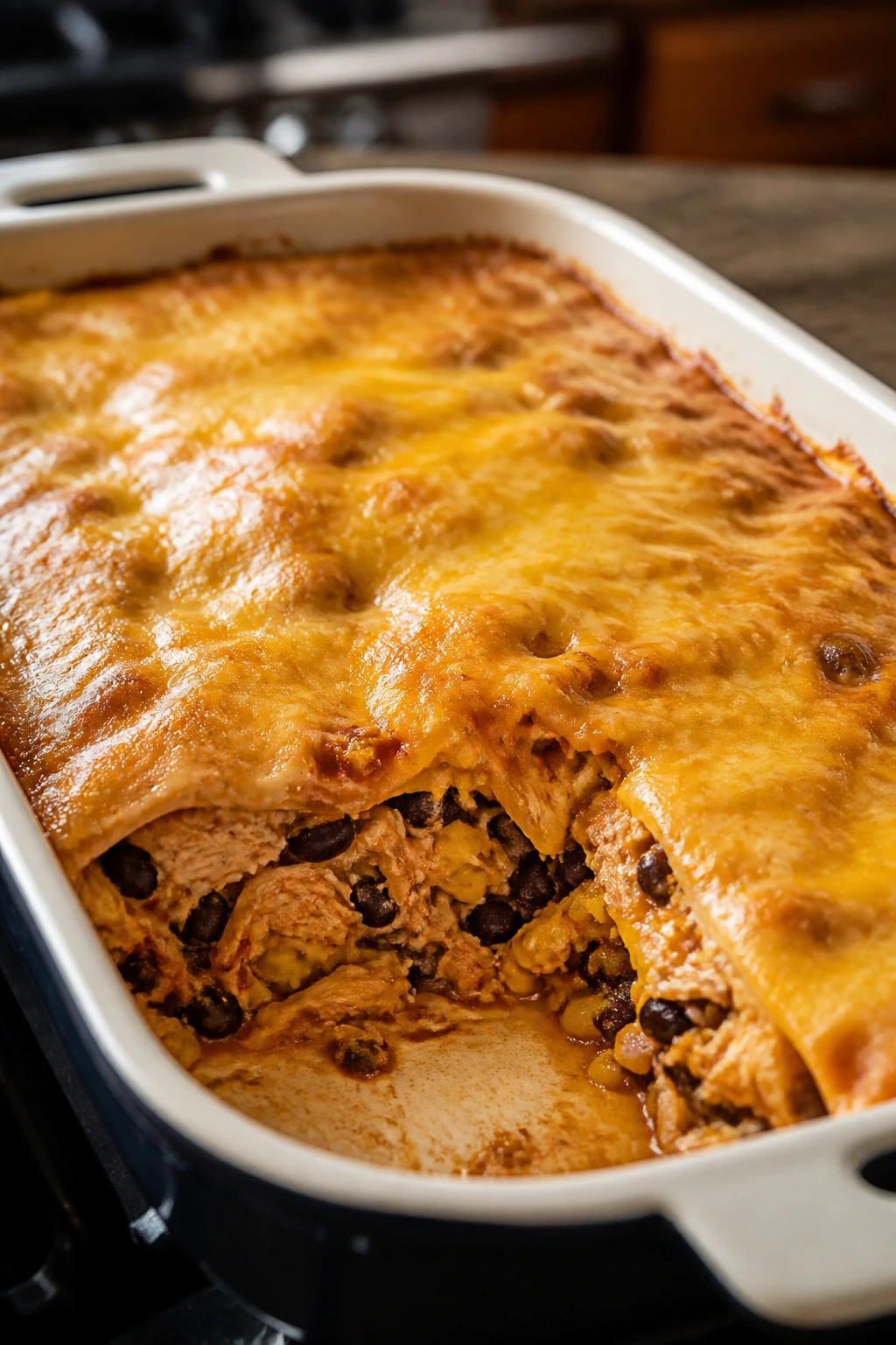 Layered chicken enchilada casserole in a baking dish with melted cheese