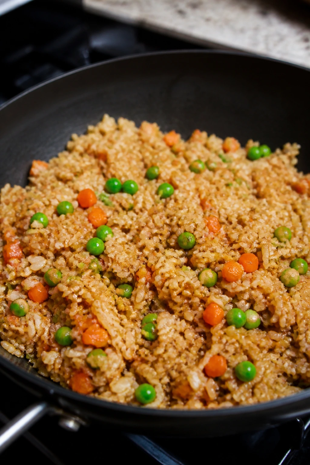 Close-up of fried rice with garlic and frozen vegetables in a skillet