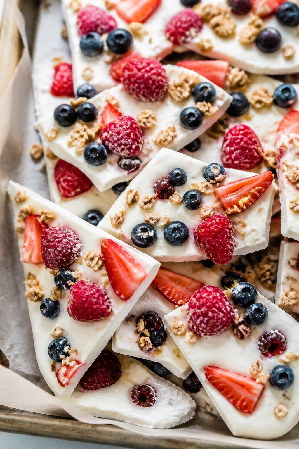Close-up of Frozen Yogurt Berry Bark shards on parchment.