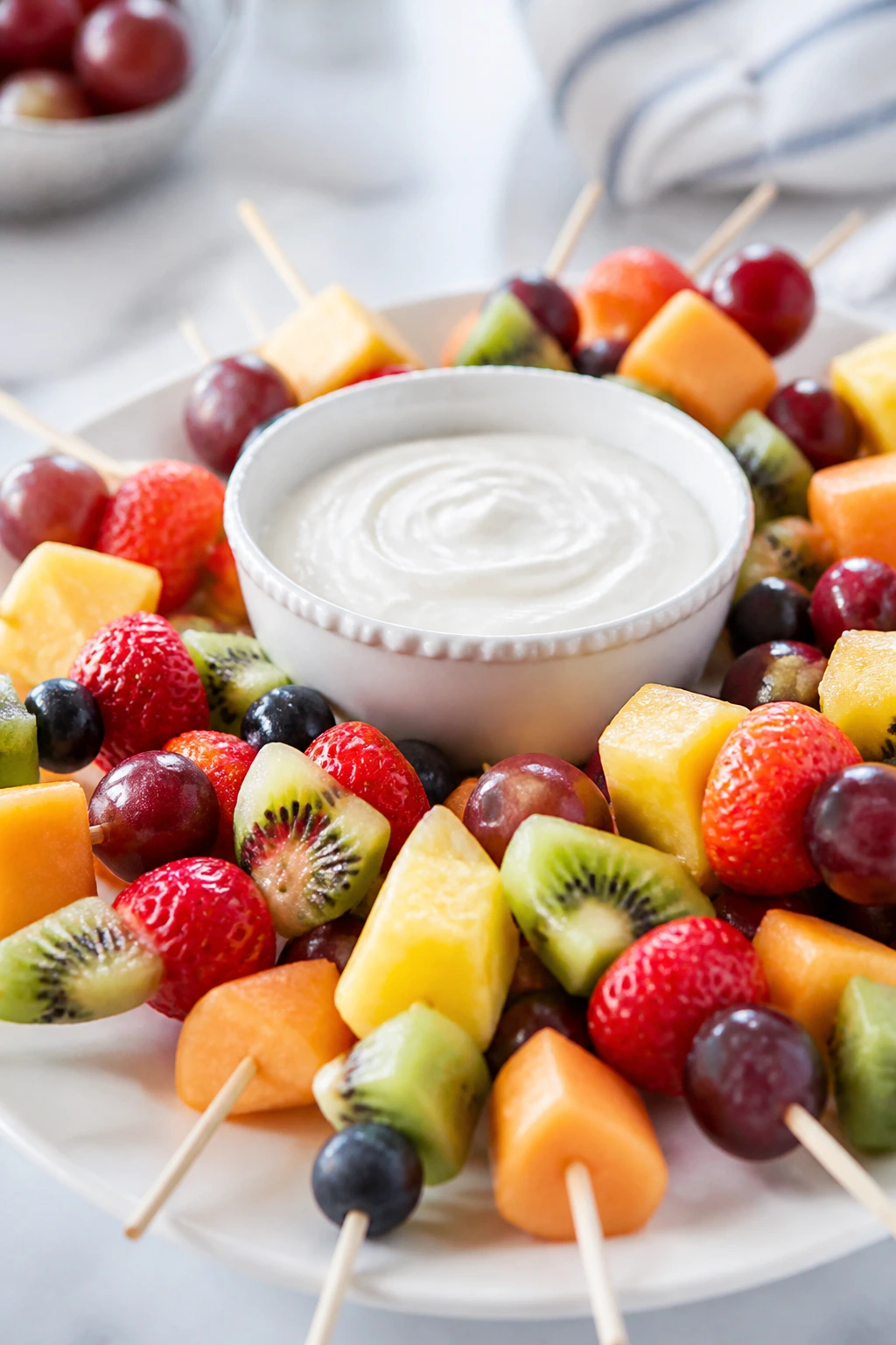 Close-up of fruit skewers with yogurt dip on a bright kitchen counter