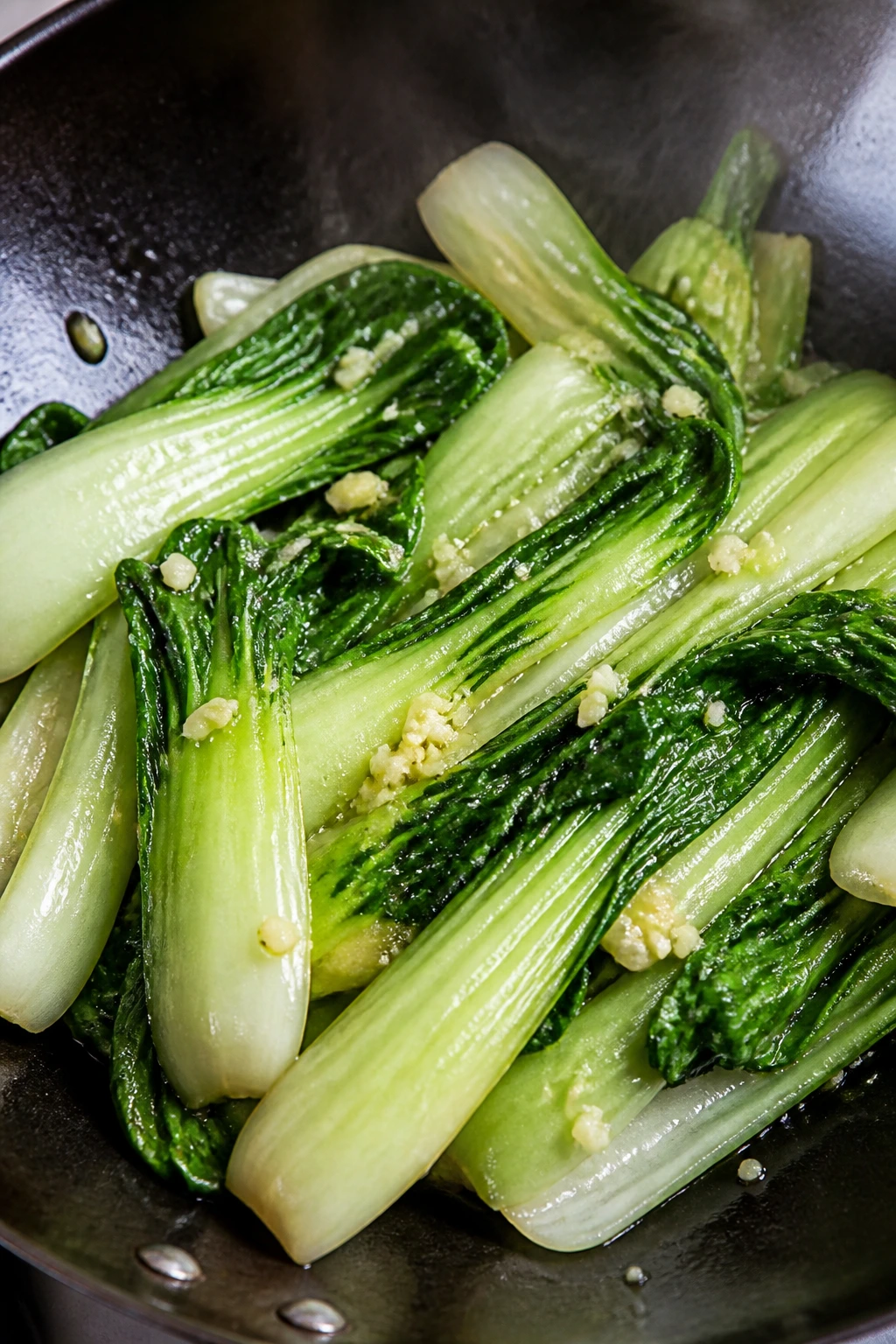 Close-up of garlic bok choy greens with garlic on a warm stove