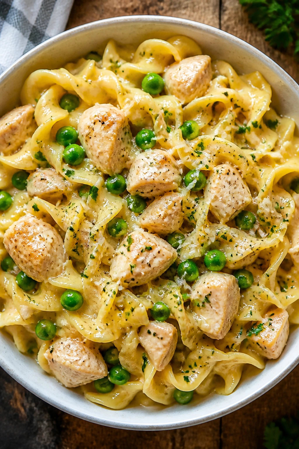 Close-up of garlic butter chicken noodles with peas in a glossy sauce