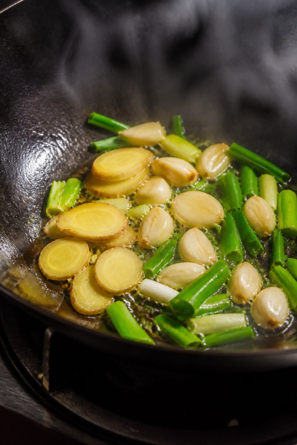 Ginger, garlic, and scallions sizzling in oil in a wok