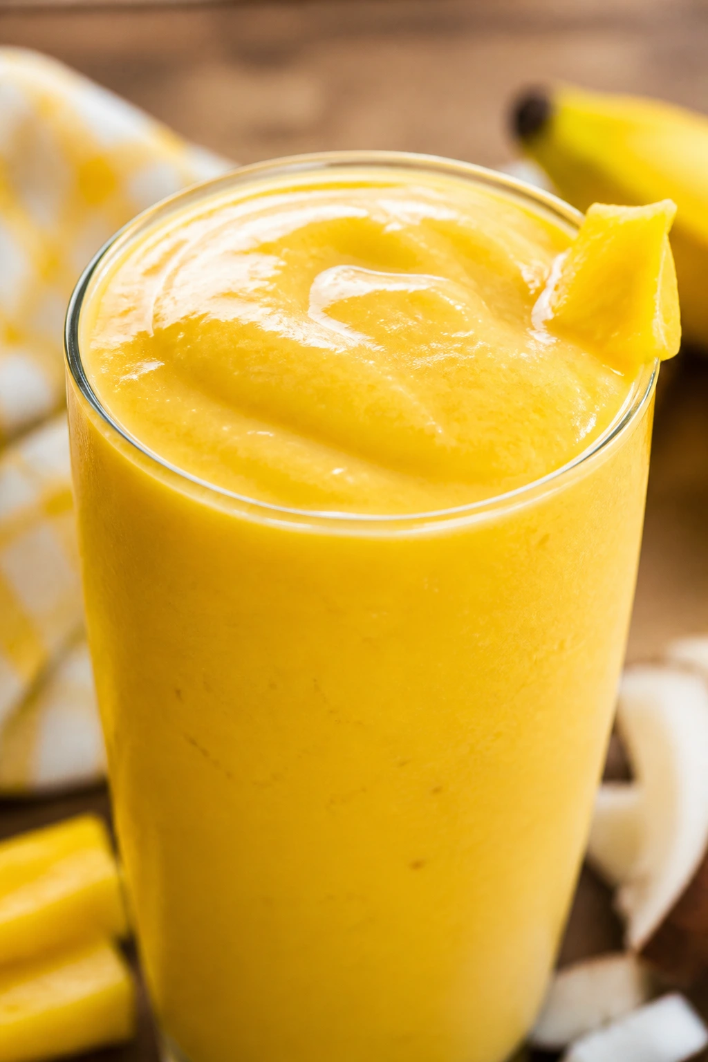 Thick golden Jackfruit Banana Coconut Smoothie in a glass on a sunlit breakfast table