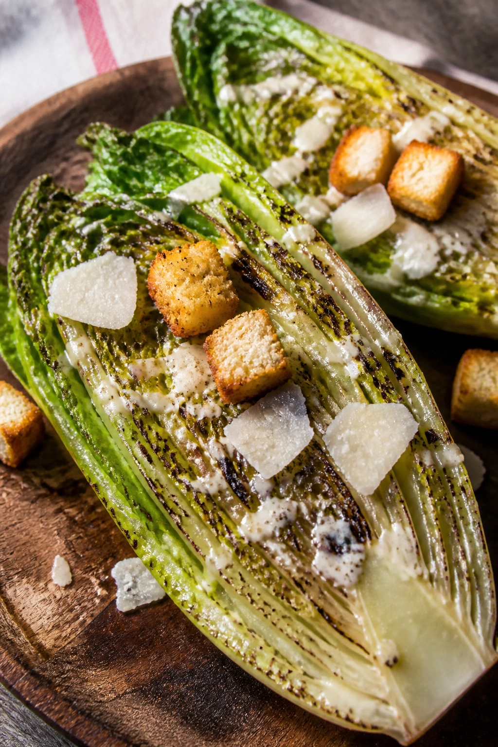 Close-up of grilled romaine halves with Caesar dressing and parmesan croutons