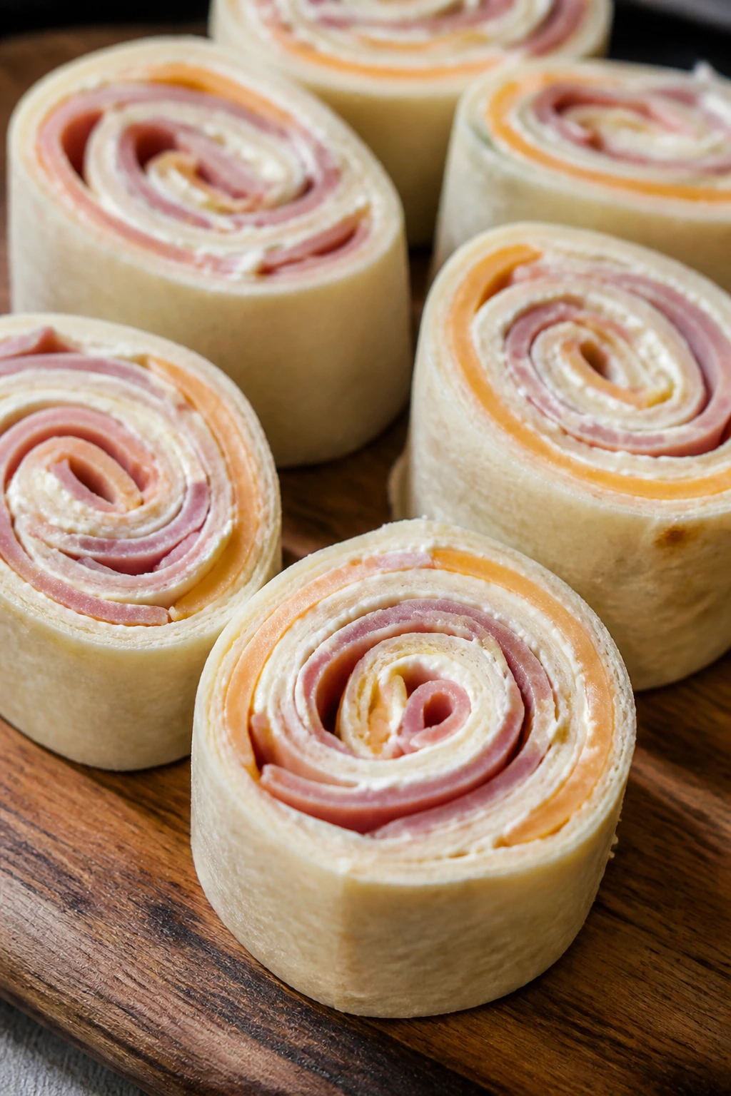 Close-up of ham and cheese pinwheels on a wooden board