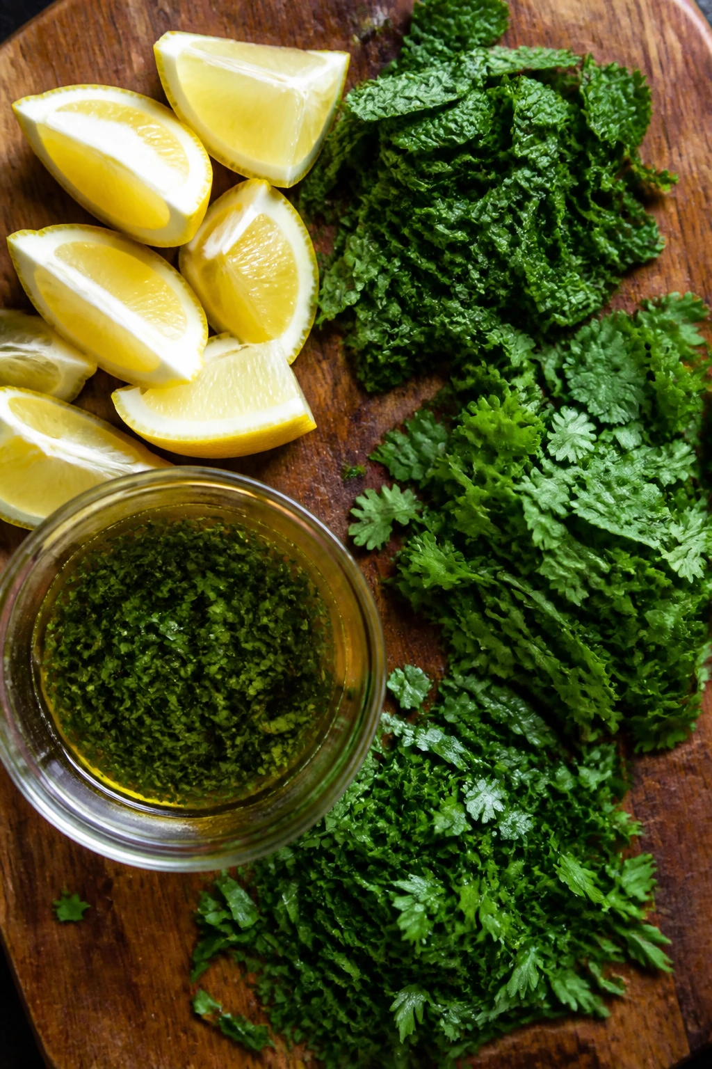 Lemons, herbs, and herb oil arranged on a wooden board
