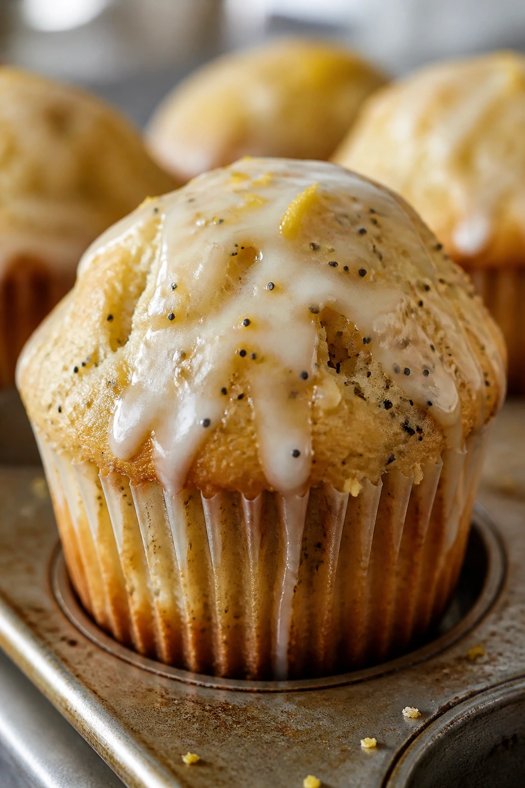 Close-up of lemon poppy seed muffin with glaze and seeds.
